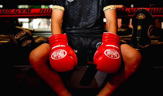 Junior boxer wearing red boxing gloves for training.
