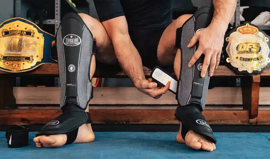 Coach tightening calf strap of a fighter's shin guard