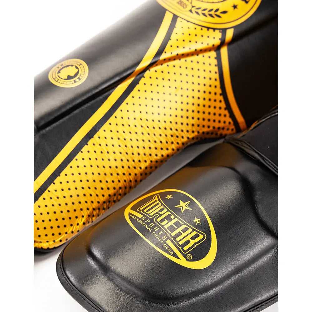 Close-up of gold TOPGEAR Fight Club shin guard showing dotted side panel design and TOPGEAR foot guard logo