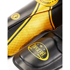 Close-up of gold TOPGEAR Fight Club shin guard showing dotted side panel design and TOPGEAR foot guard logo